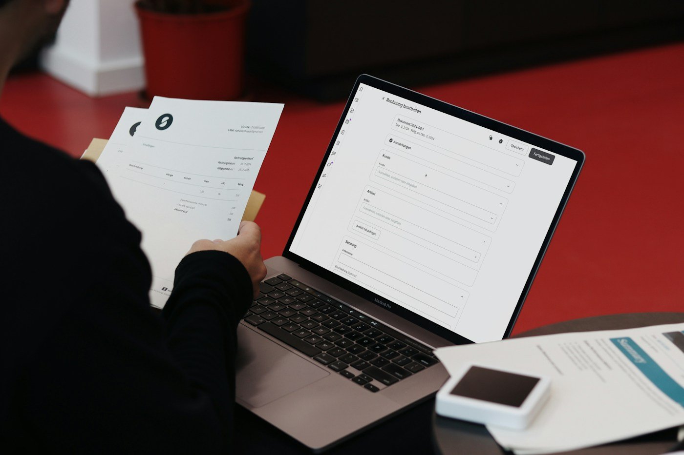 Pessoa trabalhando com computador e documentos de papel, em fotografia ilustrativa.